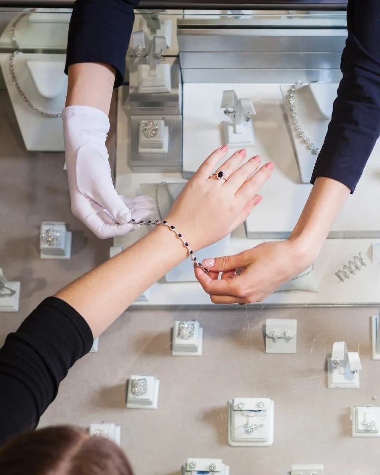 Jewelry store employee helping customer try on a bracelet and ring in Orlando