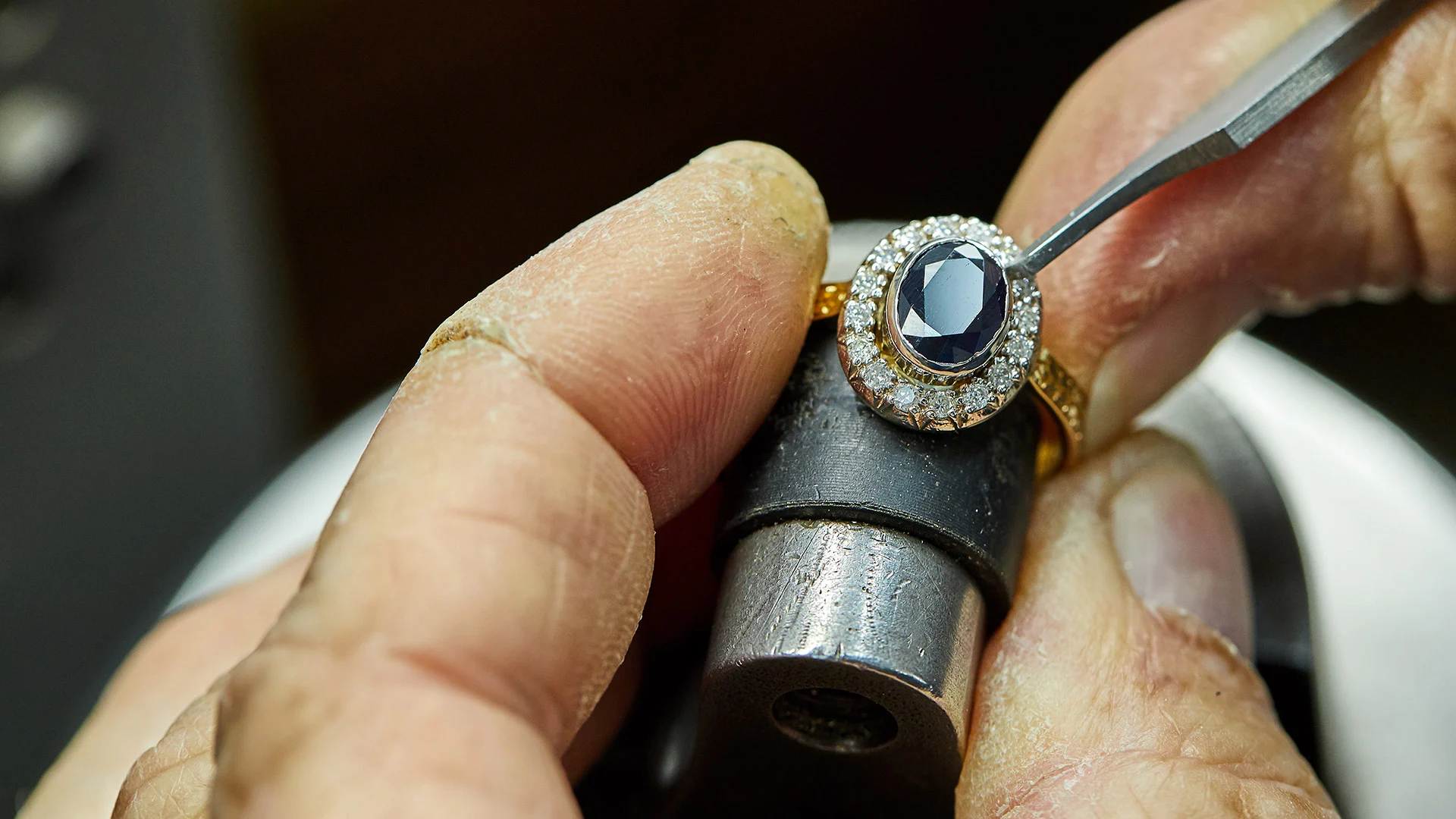 Jeweler's hands setting a sapphire and diamond ring in Orlando